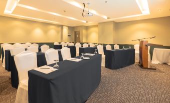 a conference room set up for a meeting , with tables and chairs arranged in rows at The Monarch Hotel