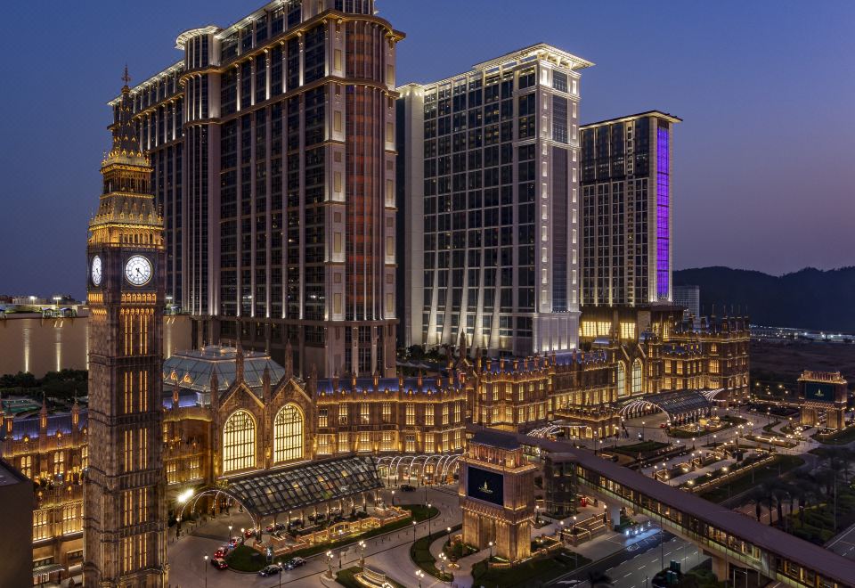 The city at night features a prominent clock tower surrounded by various buildings at Sheraton Grand Macao