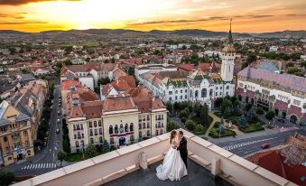 a newlywed couple standing on a rooftop with a beautiful sunset in the background , holding hands at Grand Hotel