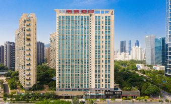 In the background, there are tall buildings, including an office tower, behind a large building with many windows at Hisoar Hotel