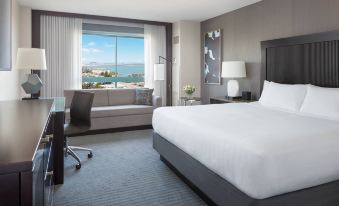 a large bed with a white comforter is in the middle of a room with a window overlooking the ocean at Hyatt Regency San Francisco Airport