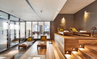 a modern living room with wooden floors , large windows offering views of the city , and comfortable seating arrangements at HYPERION Hotel Leipzig