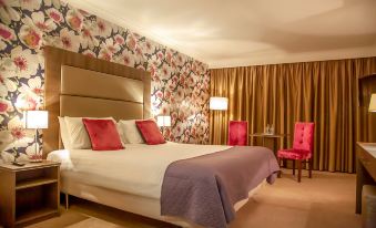 a large bed with a purple blanket and red pillows is in a room with floral wallpaper at Brandon House Hotel