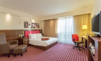 a hotel room with a large bed , a chair , and a television mounted on the wall at Hampton by Hilton Exeter Airport