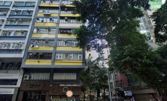 A tall building with apartments in the middle and other buildings on either side in an urban setting at J Link Hotel