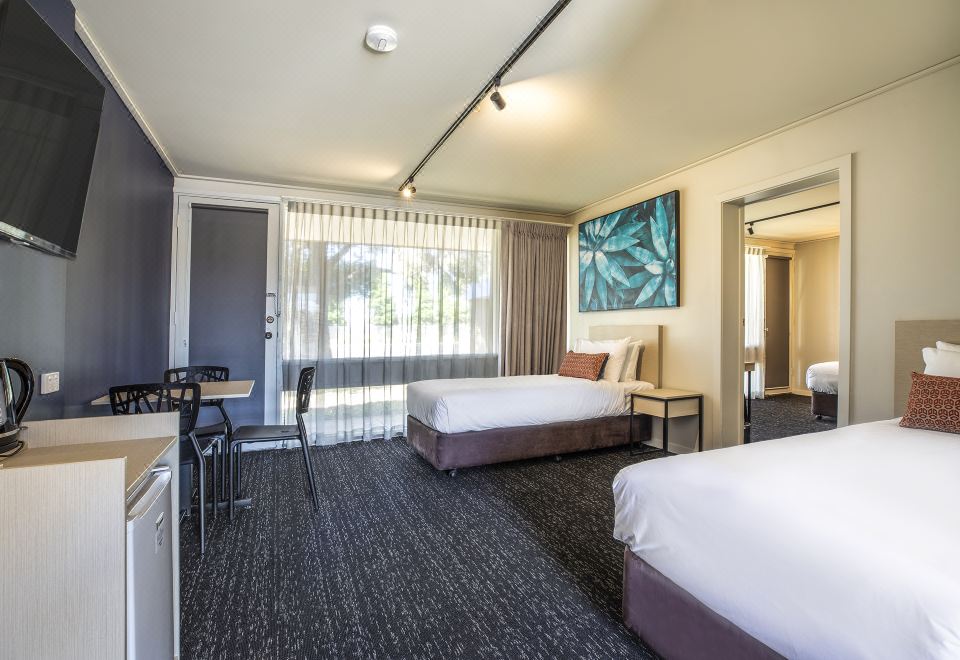 a modern hotel room with two beds , a desk , and a window , decorated in white and gray colors at Nightcap at Gateway Hotel