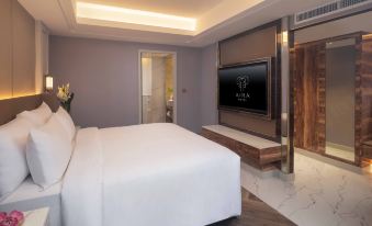 The bedroom features a large bed with a flat-screen TV mounted on the wall above it at Aira Hotel Bangkok Sukhumvit 11