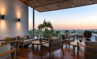 a modern outdoor living area with wooden flooring , stone flooring , and glass walls , overlooking the ocean at sunset at Mediterranean Beach Hotel
