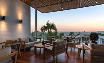 a wooden terrace with lounge chairs and tables , offering a view of the ocean at sunset at Mediterranean Beach Hotel