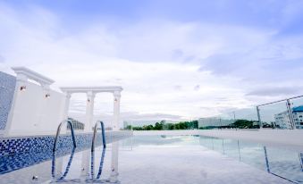 An empty resort features a swimming pool with blue water and a white sand beach in the background at B2 Phuket Premier Hotel