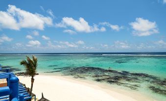 a beautiful beach with clear blue water , white sand , and a few palm trees in the background at Salt of Palmar, Mauritius