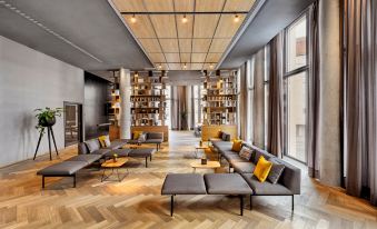 a modern living room with wooden floors , large windows , and comfortable couches arranged in a cozy seating area at HYPERION Hotel Leipzig