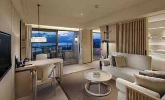 The living room, with its large windows and balcony offering ocean views, features an elegant couch at Hilton Shenzhen Shekou Nanhai