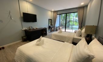 a hotel room with two beds , a desk , and a sliding glass door leading to a balcony at Maikaew Damnoen Resort