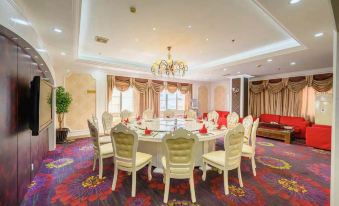 a formal dining room with a large table surrounded by white chairs , and a chandelier hanging above at Diamond Hotel