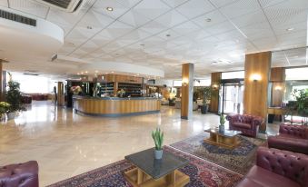 a spacious hotel lobby with a large reception desk and several potted plants , creating an inviting atmosphere at Hotel Minerva