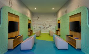 a room with a blue and green floor , two white chairs , and a television on a wall at Rixos Water World Aktau