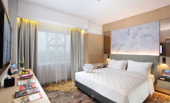 a large bed with white linens is in a room with a window and a nightstand at Swiss-Belinn Modern Cikande