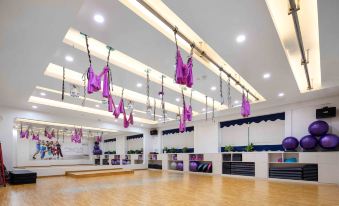 a large , well - lit room with pink and purple lounge chairs hanging from the ceiling , creating a vibrant atmosphere at Golden Hotel