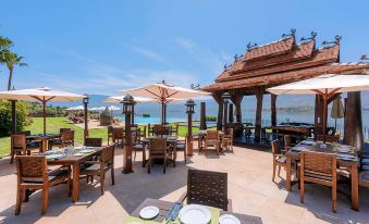 an outdoor dining area with wooden tables and chairs , surrounded by a gazebo overlooking the ocean at Widiane Resort