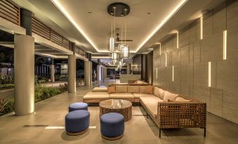 a modern living room with multiple couches , chairs , and tables arranged around a central area at Mambruk Hotel & Convention