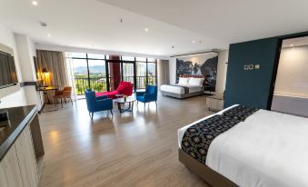 a spacious bedroom with a king - sized bed , multiple chairs , and a large window overlooking the mountains at Travelodge Ipoh