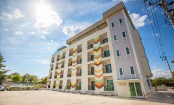 a multi - story building with colorful stripes on its exterior , situated in a parking lot under a blue sky at IRabbit Hotel