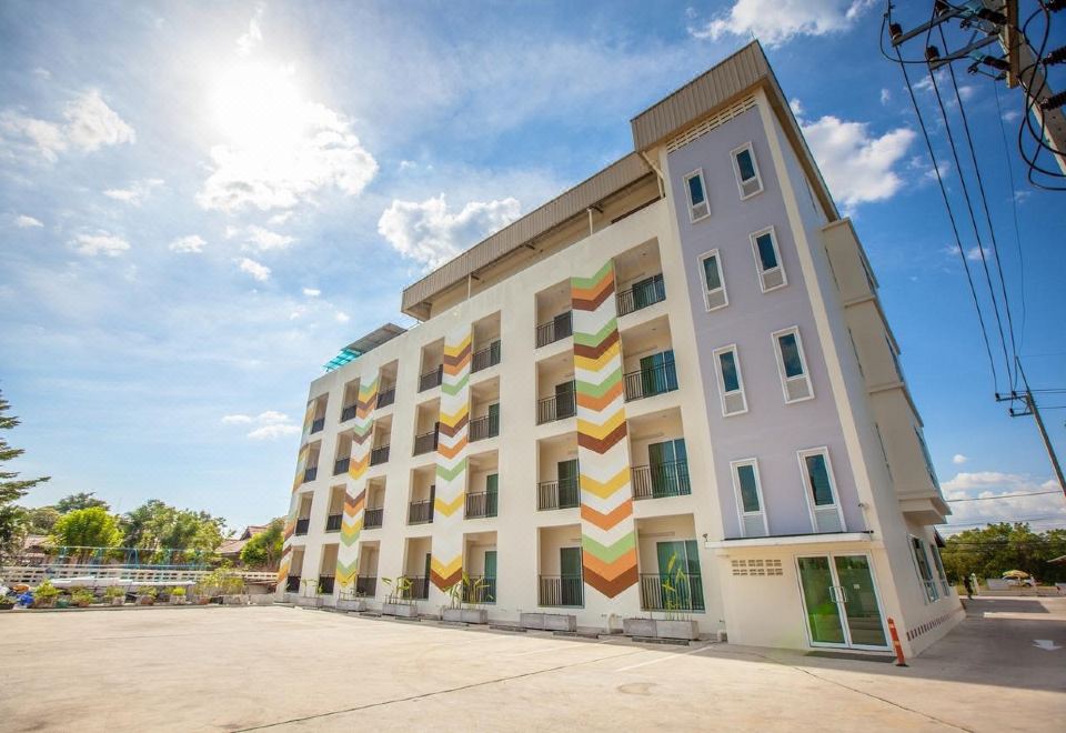 a multi - story building with colorful stripes on its exterior , situated in a parking lot under a blue sky at IRabbit Hotel