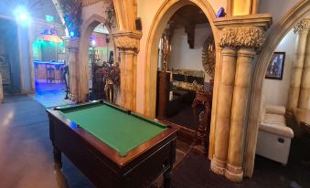 a billiards table in a room with stone walls and arches , surrounded by other furniture at Empire Hotel