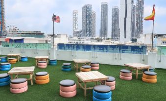 a rooftop bar with colorful stools and tables , surrounded by a green lawn and tall buildings in the background at Best Western I-City Shah Alam