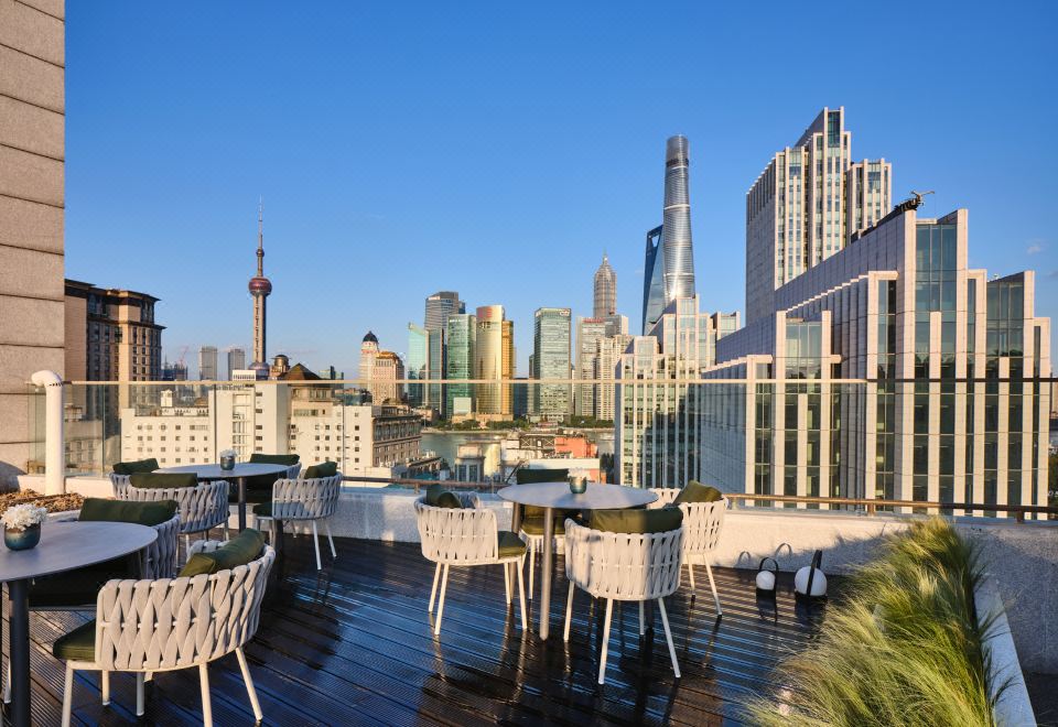 There is a rooftop balcony on an upper floor with tables and chairs that provide a view of the city at Blossom House Shanghai On The Bund