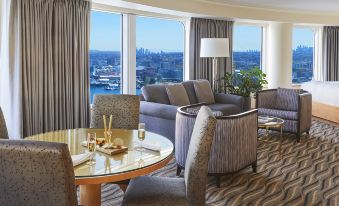 a modern living room with a couch , chairs , and dining table in front of large windows at Pan Pacific Vancouver