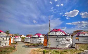 A cluster of tents stands in the center with a clear blue sky as the backdrop at Colorful Danxia Yimi Sunshine Inn