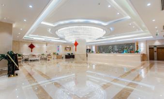 a luxurious hotel lobby with a white marble floor , a large chandelier hanging from the ceiling , and a marble reception desk at Vienna Hotels