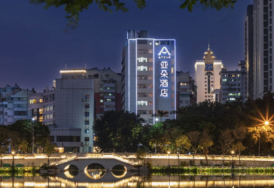 a city skyline at night , with a bridge crossing over a body of water in front of a tall building at Atour Hotel