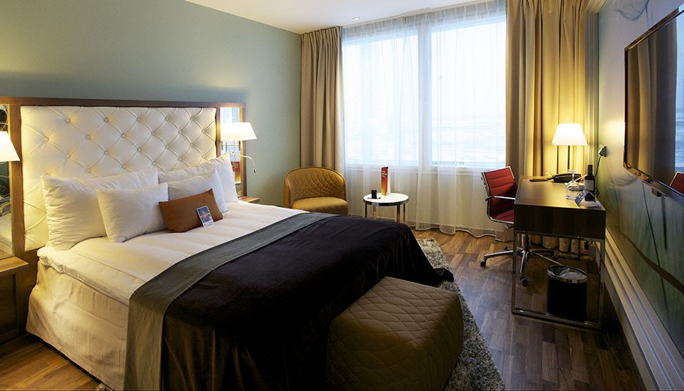 a hotel room with a king - sized bed , two chairs , and a window overlooking the city at Clarion Hotel Arlanda Airport Terminal