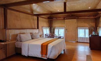 a large bed with white linens and a wooden headboard is in the center of a room with wooden floors at Khas Parapat