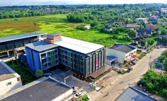 a modern building with a green roof is situated in a rural area with buildings and trees at Siva Royal Hotel