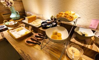 a dining table with a variety of food items , including bread , pastries , and bowls filled with various ingredients at Huis Ten Bosch