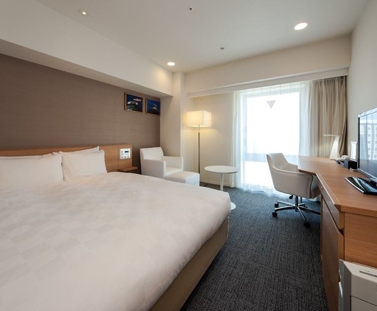 a hotel room with a large bed , a desk , and a window overlooking the ocean at Daiwa Roynet Hotel Numazu