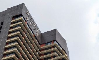 The front view and sign of a hotel in an urban setting with tall buildings on either side at Moka Apartment (Guangzhou CUHK Cancer Hospital Taojin Subway Station)