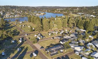 an aerial view of a small town with a lake in the background , surrounded by houses and trees at Nrma Sydney Lakeside Holiday Park