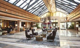 In the middle of the lobby, there are chairs and tables positioned next to an arched doorway at Kempinski Hotel Beijing Yansha Center