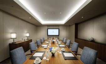 a conference room with a wooden table , blue chairs , and a projector screen , set up for a meeting at Halekulani Okinawa