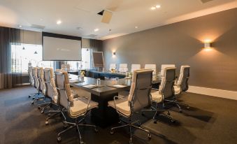 a conference room with a large table , chairs , and a projector screen , ready for meetings or presentations at Van der Valk Volendam