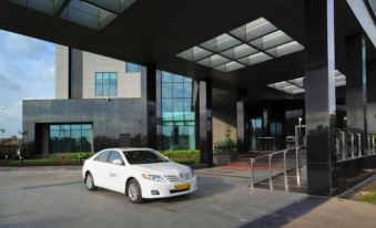 a white car is parked in front of a building with a large glass window at Radisson Hotel New Delhi Paschim Vihar