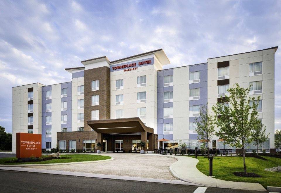 a large , modern hotel with a gray and brown color scheme , surrounded by trees and a clear sky at TownePlace Suites Memphis Southaven