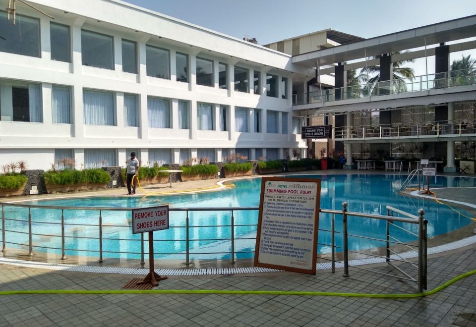a large outdoor swimming pool surrounded by a building , with several people enjoying their time in the water at Hotel Miramar