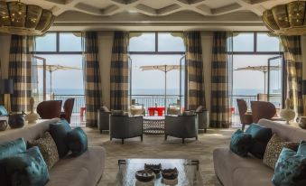 a living room with large windows offering an ocean view , surrounded by comfortable furniture and a glass coffee table at Four Seasons Hotel Tunis