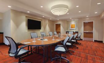 a conference room with a wooden table surrounded by chairs and a tv mounted on the wall at Hilton Garden Inn Falls Church